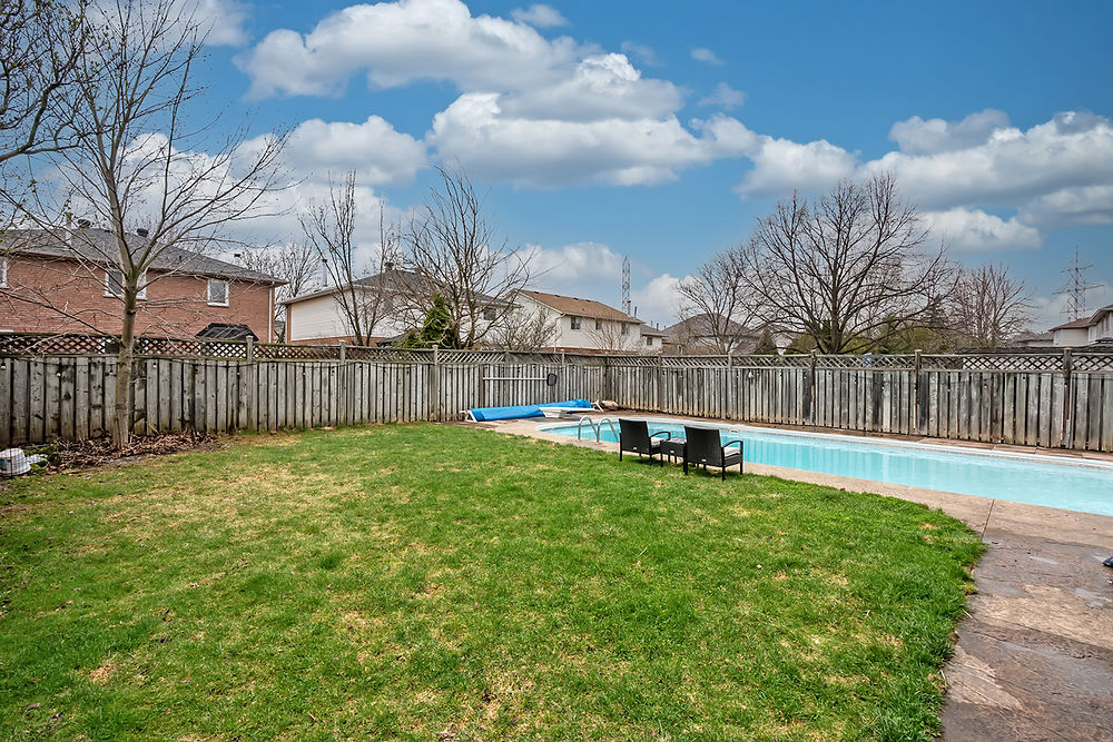 Residential backyard with swimming pool and green lawn