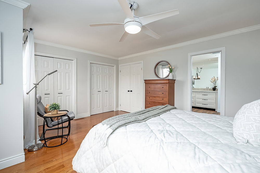 Bright bedroom with white bed, closet, and bathroom view