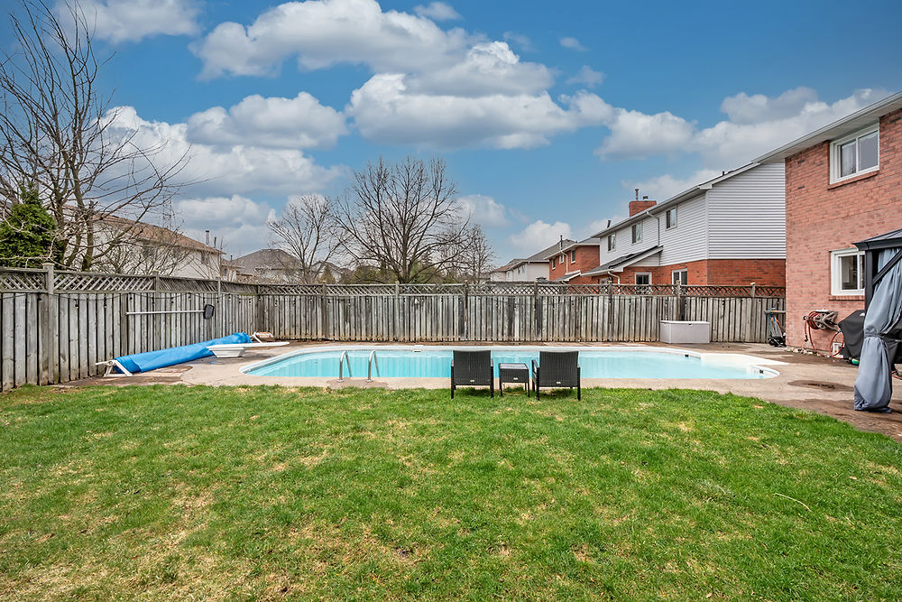 Backyard swimming pool with lounge chairs and green grass