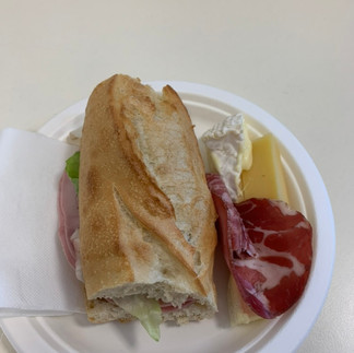Sub sandwich with ham, cheese, and sliced salami on a white plate.