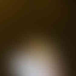 Hand holding a folded crepe wrapped in newspaper on a cobblestone street.