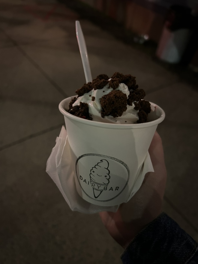 Handheld cup of Dairy Bar soft serve ice cream topped with chocolate cookie crumbles.