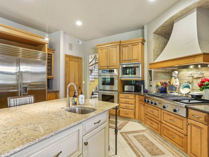custom kitchen with decorative tile flooring and large range hood and oak custom cabinets