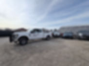 White F250 TAKERS Towing Truck with White 2025 Hyundai Palisade on tow lift. Beautiful Sunset with impounded cars around.