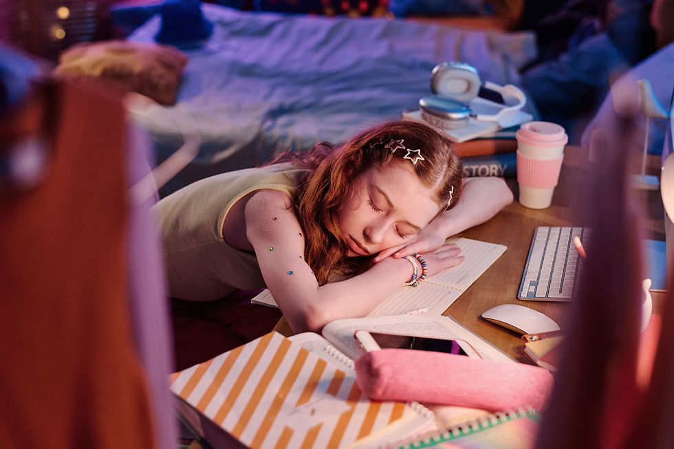 A teenage girl asleep at her desk