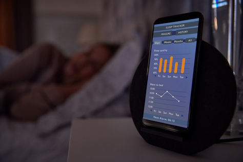 Sleep tracker app on a phone screen next to someone's bed