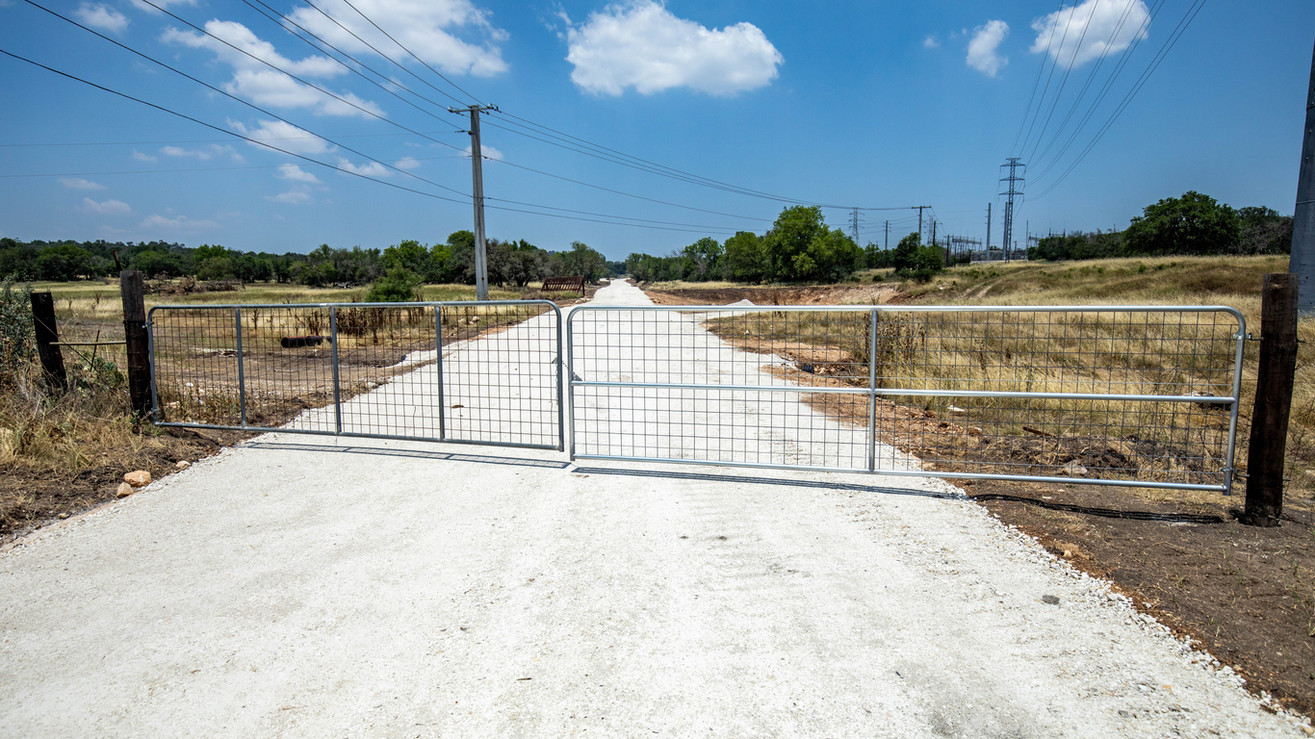 Metal gate blocking a gravel road leading into Steel Creek Estates, TX