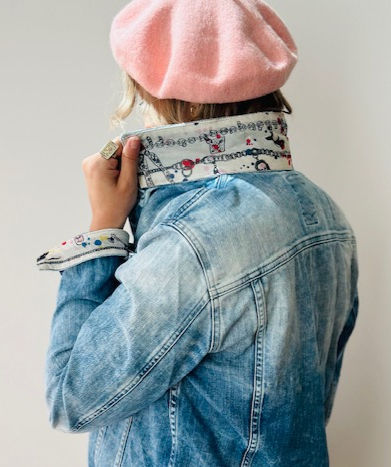 A woman shows off the collar of her jean jacket with an Alexander McQueen scarf sewn on it