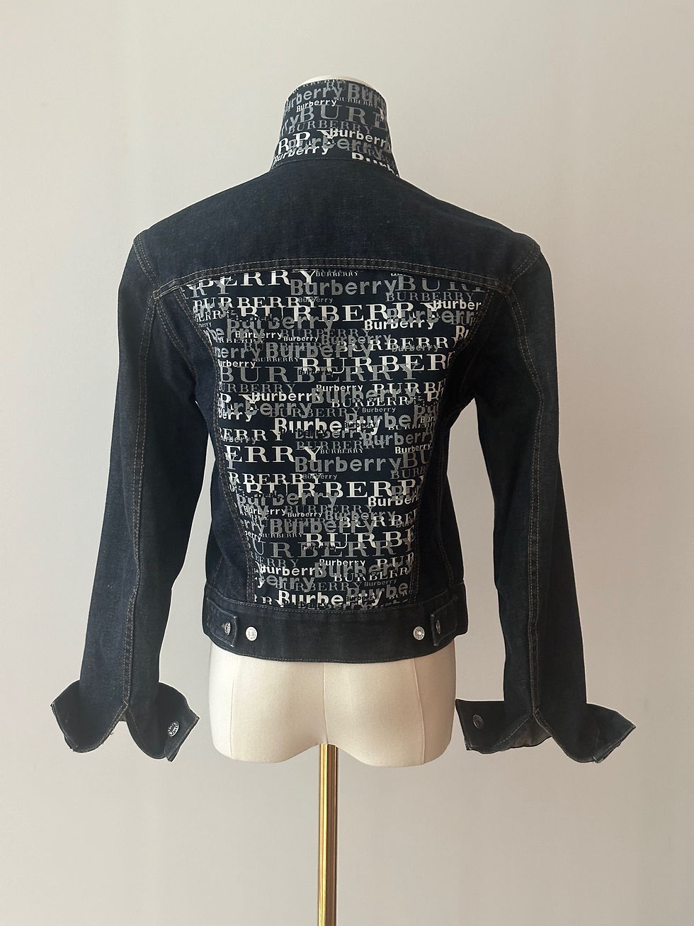 Thumbnail: The back view of a denim jacket with a Burberry scarf sewn on it