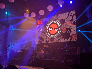 an event stage sporting the rocket beans logo behind musical equipment