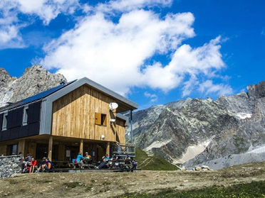 Randonneurs partageant un repas convivial dans un refuge de montagne au coucher du soleil.
