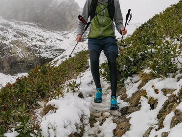 Coureur en crête alpine entre trail et alpinisme, face à des sommets enneigés