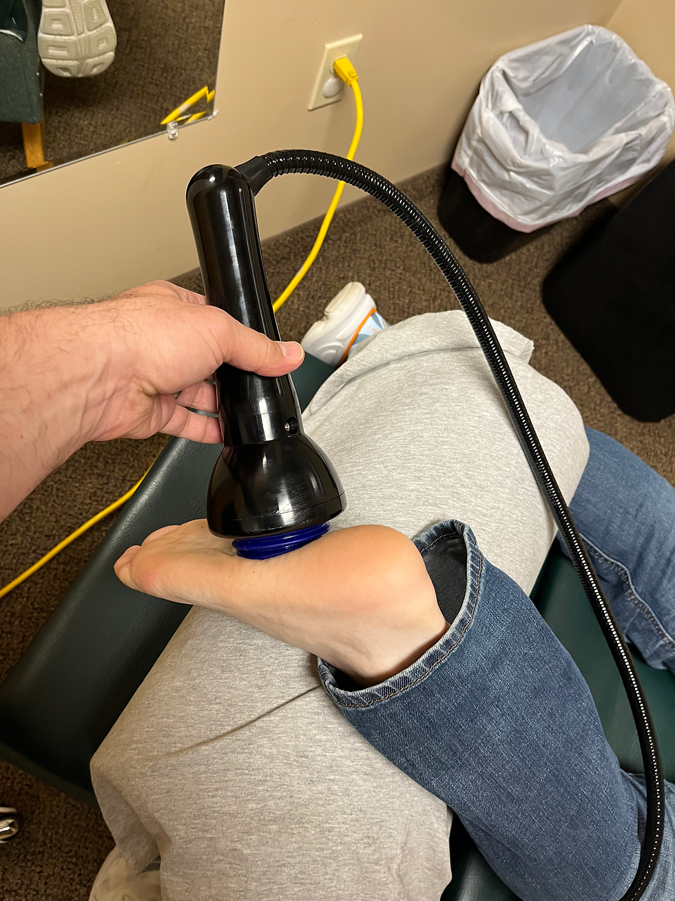 Dr. Eric Hahn applying OmniWave Shockwave Therapy to a patient's heel for plantar fasciitis treatment at Oasis Chiropractic & Wellness Center in Cottage Grove, MN