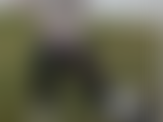 A person happily raking autumn leaves in their yard using proper posture, demonstrating chiropractor-approved techniques to prevent back and shoulder pain.