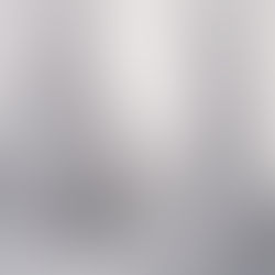 Tief verschneite Tannen im Nebel, durch den die Sonne scheint.