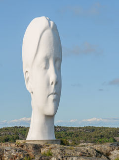 Eine Skulptur, ein großer weißer Frauenkopf, auf einem Felsen