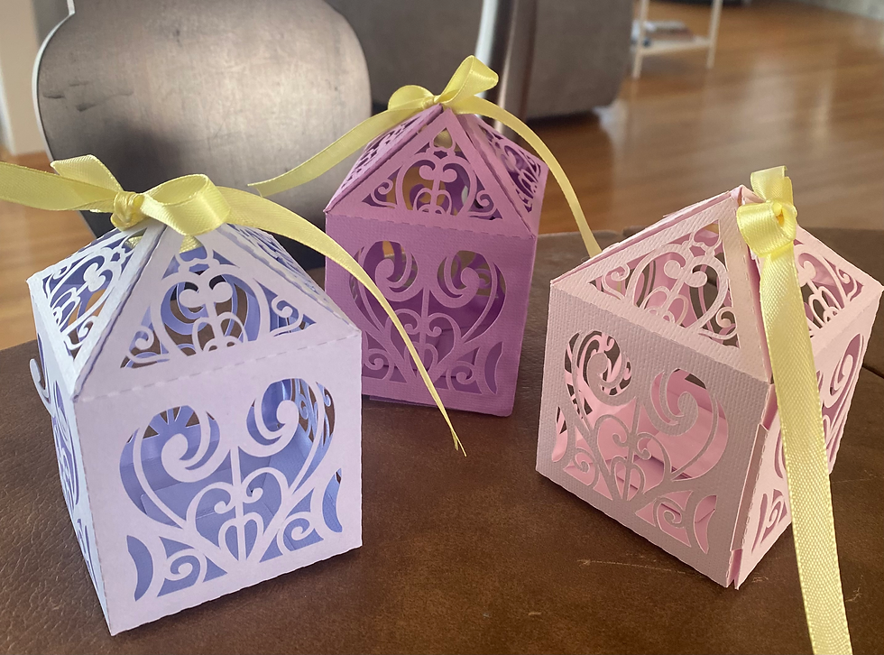 Three decorative paper boxes with heart cutouts and yellow ribbons