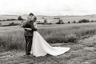 Bride and groom embrace in field; A glorious Farm Wedding in Aldbourne, Wiltshire.