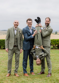 Four men pose for picture; one man upside down with his friends.