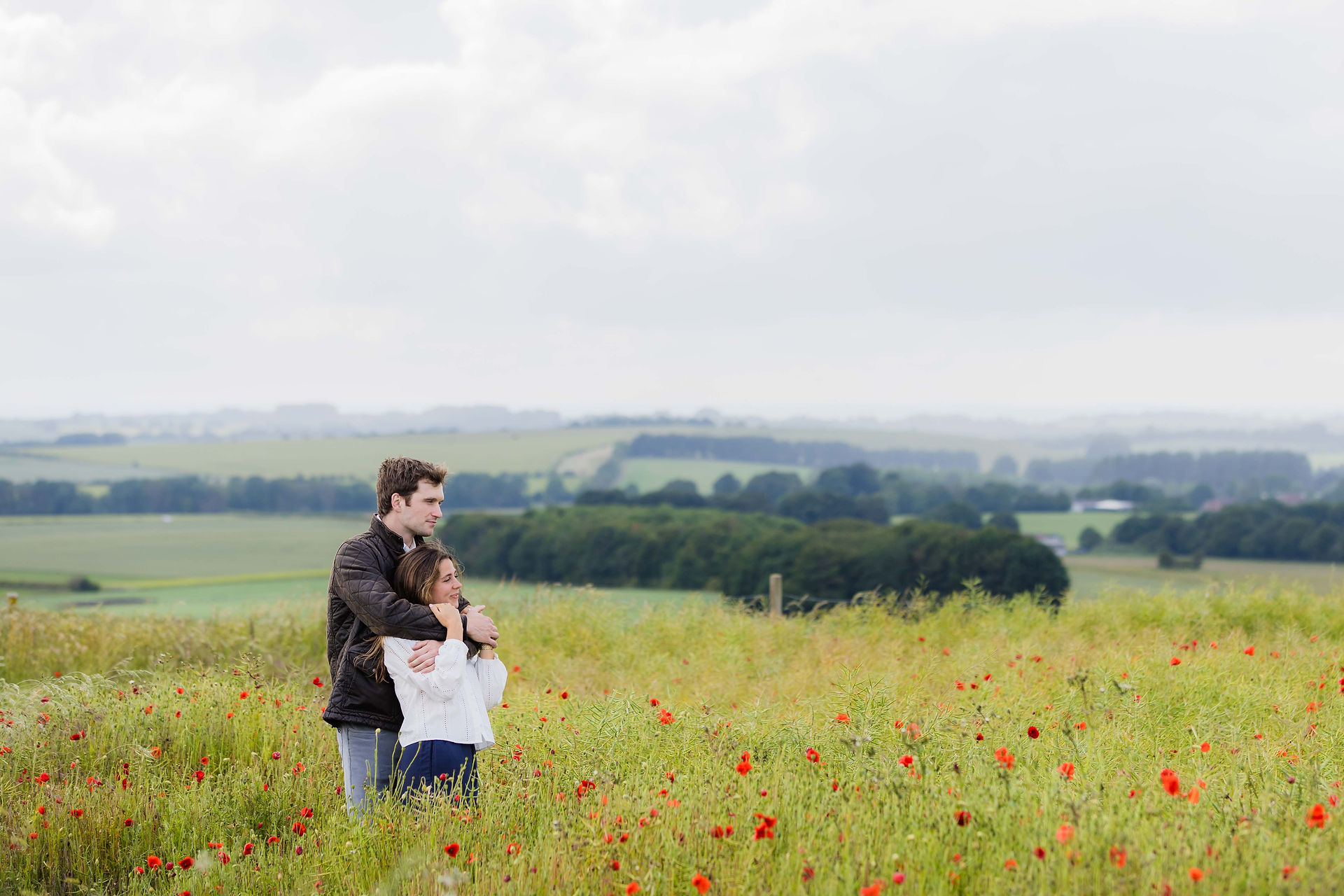 Young couple embracing in a field of wildflowers, enjoying the scenic view.