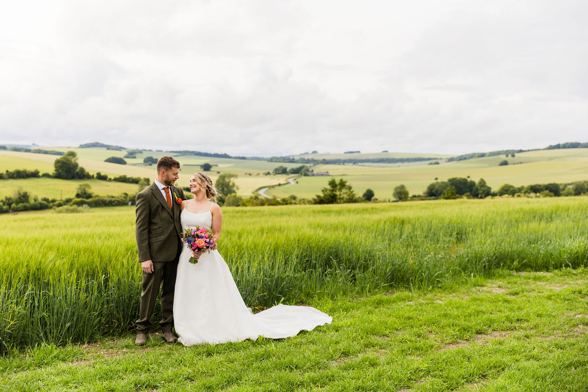 Couple at wedding, happy, looking at each other in a field. A glorious Farm Wedding in Aldbourne, Wiltshire.