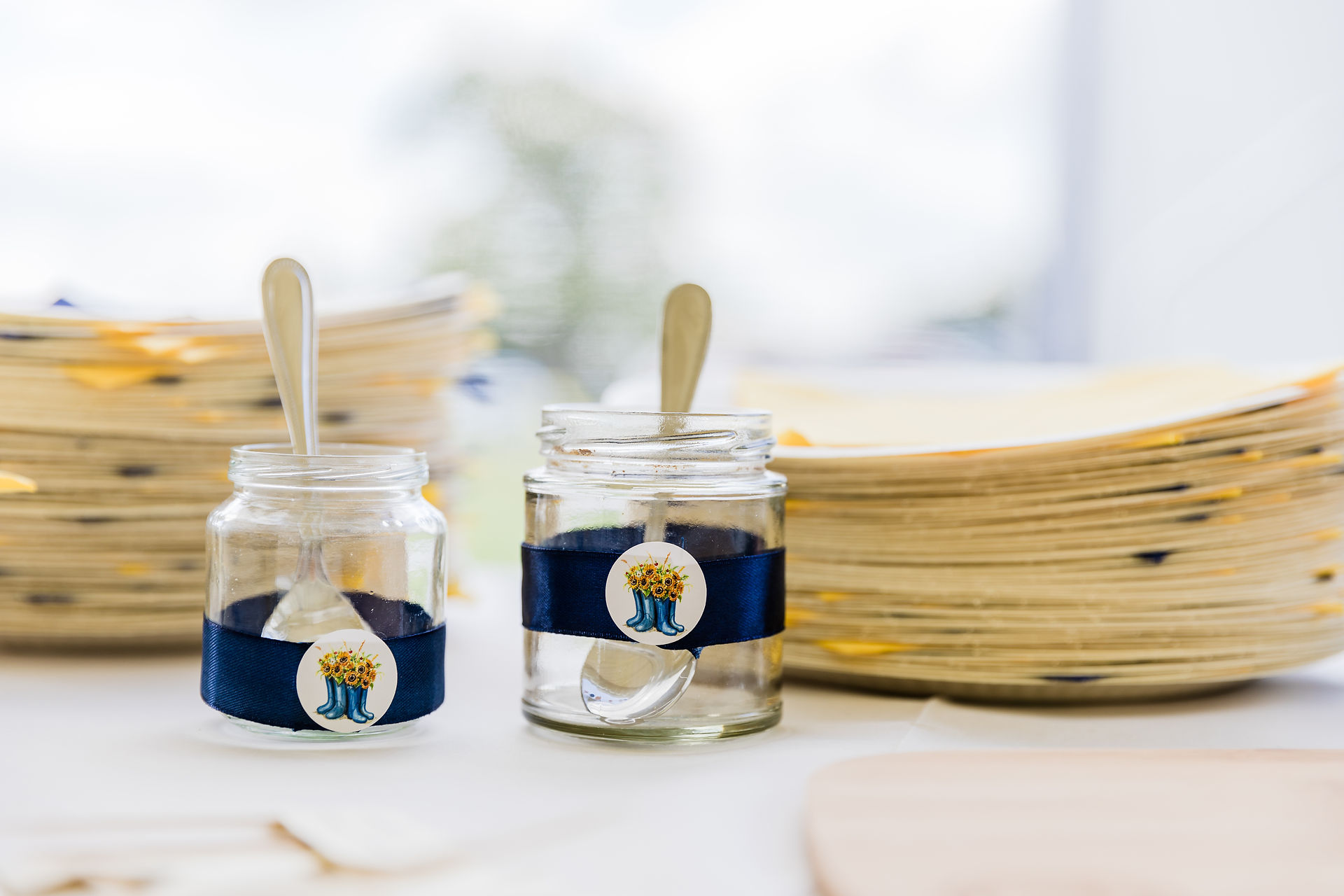 Two glass jars with spoons and blue ribbon detail on white table