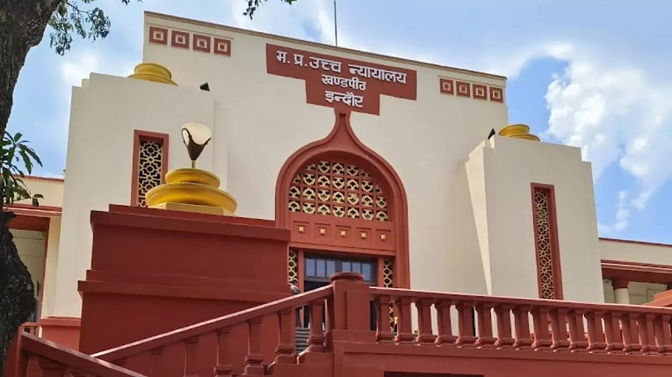 Red and cream building with arched windows, intricate detailing, and a sign in Hindi. Blue sky and tree branches are visible.