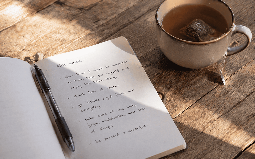 High angle view of a cozy space with a journal, pen, and cup of tea