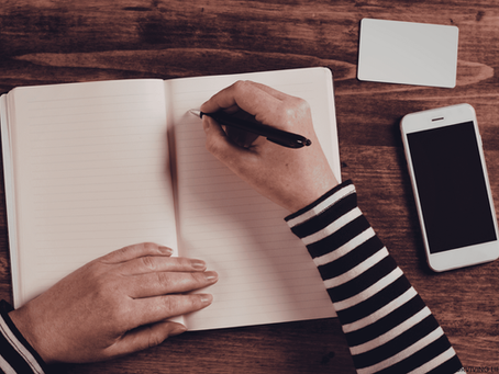 A person writing in a journal at eye level, focusing on the act of self-reflection
