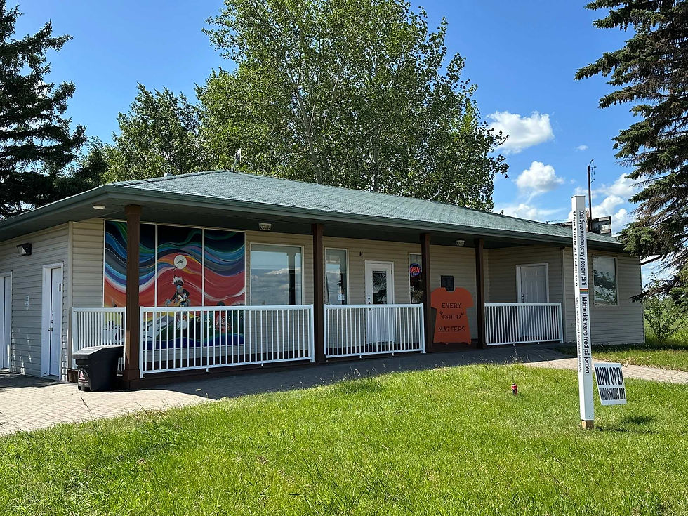 a building of the Skydancer centre. In front is a proch with white fencinf. A beautiful Indigenous murla sits out front on the front of the building.