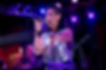 Woman singing into a microphone on stage