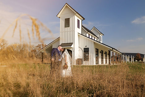 Newlyweds kissing in front of a white barn