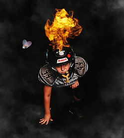 Young football player in a "Panthers" jersey crouches in a ready stance, wearing a helmet with flames digitally added above i