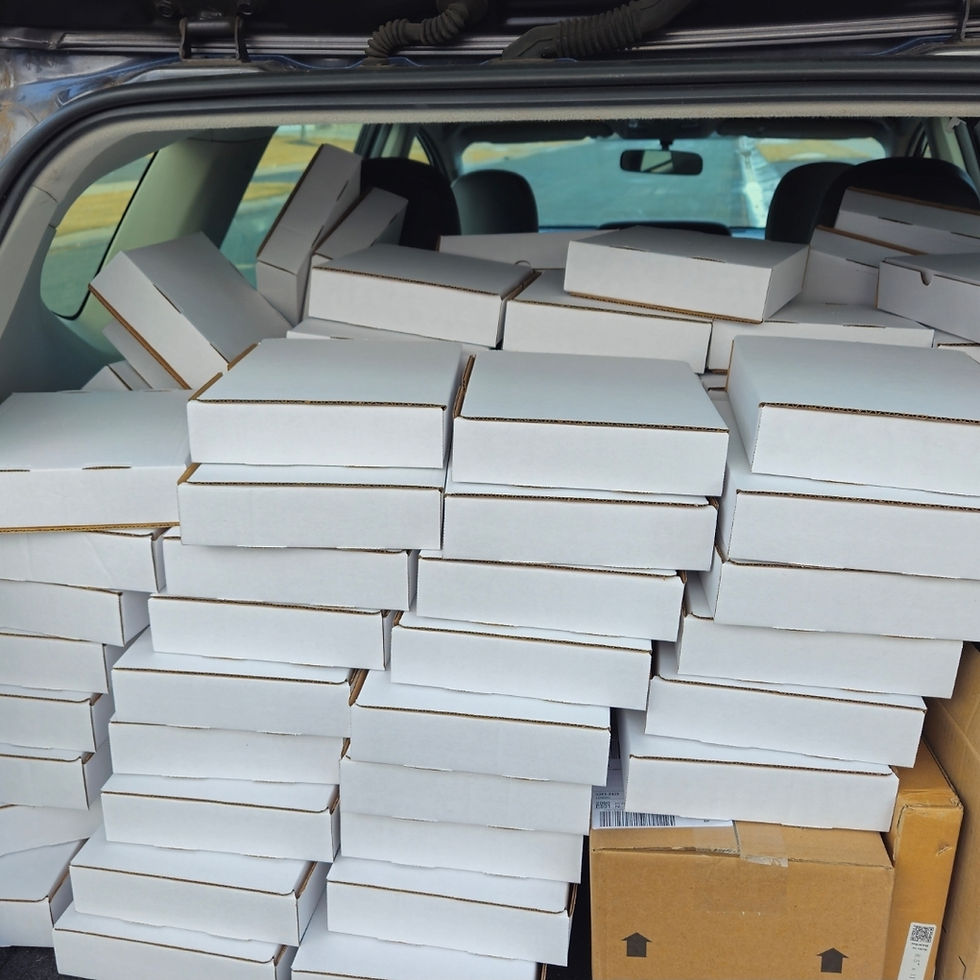 Transporting empty kit boxes after folding and preparing them for packaging. These would later hold the completed STEM boat kits.