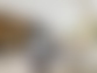 Cozy living room with beige sectional, patterned pillows, a black coffee table, built-in shelves, and a wall-mounted TV. Circular windows give soft light.