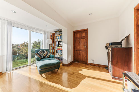 Light filled room with wooden floor and furniture and large patio doors