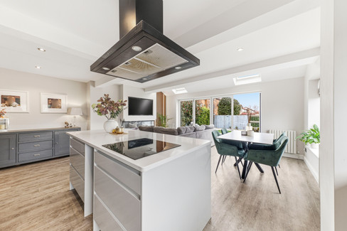 Kitchen in a bright open space with dining table and sofa in background