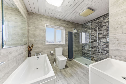 Spacious bathroom with seperate bath and shower. Grey, black & white tiles