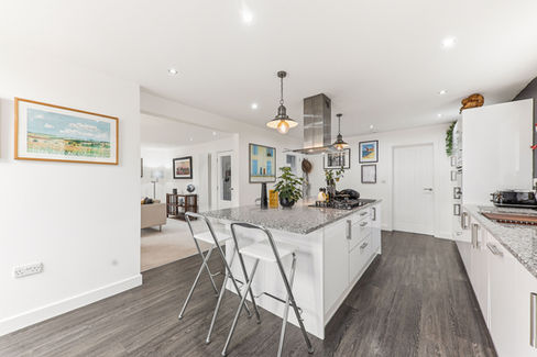 Large kitchen island with 2 bar stools, a painting on the wall, grey interiors and flooring
