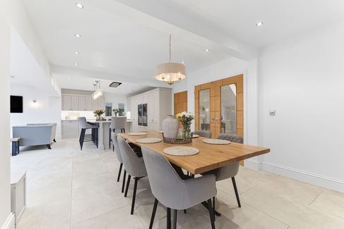 Large white kitchen with wooden dining table