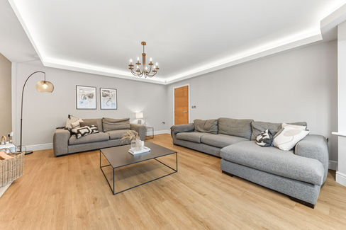 Large lounge with wooden flooring and 2 grey sofas
