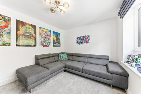 Grey L-shape sofa in white room with prints on wall
