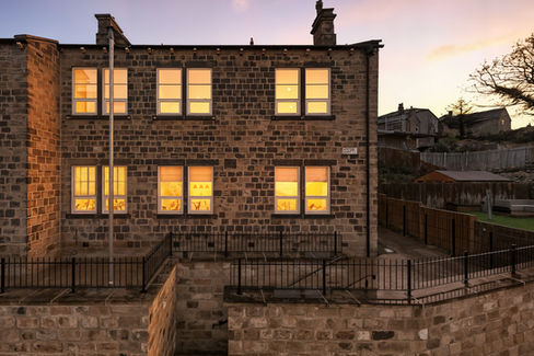 Stone apartment building with lights on inside and sunset in the sky