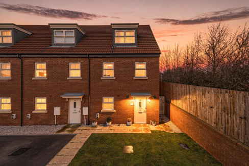 Twilight photo of end terrace property with front garden