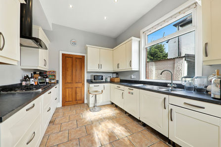 Kitchen with stone floor, wooden door and white cabinets