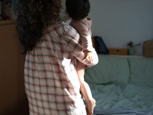 una madre soltera cargando a su niña en brazos de espaldas