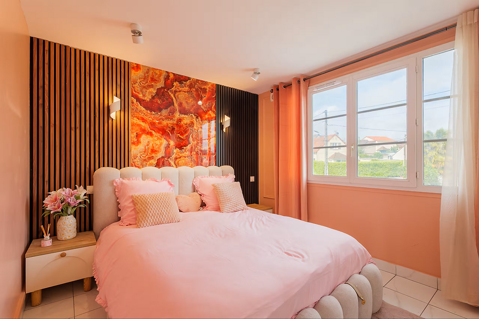 Chambre avec lit double rose, mur décoratif orange, grande fenêtre à droite, ambiance chaleureuse, format paysage