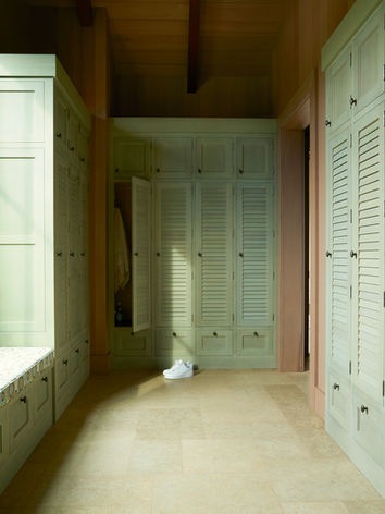 A locker room with tile floors and green louvered locker doors
