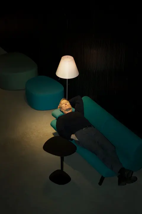 Hans Petter Moland, film director, lying on a green sofa looking up. The picture is taken from above.
