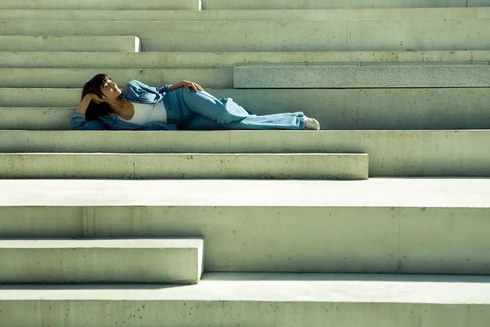 Singer/songwriter Suraya lying on a grey set of stairs.